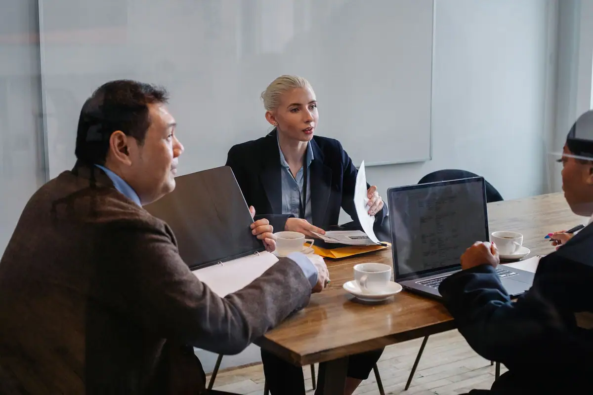 Colleagues reviewing documents and a laptop together during a business planning meeting