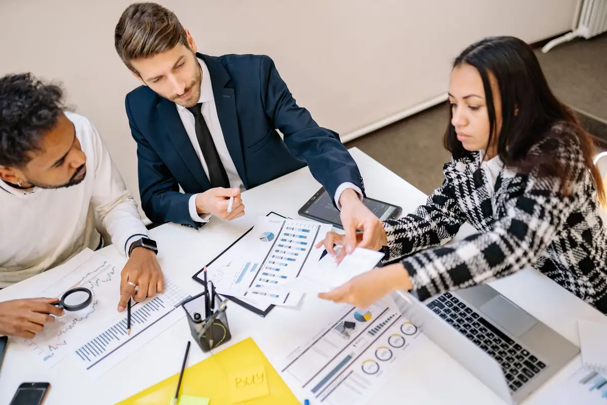 Team marking up printed charts and plans together at a shared desk