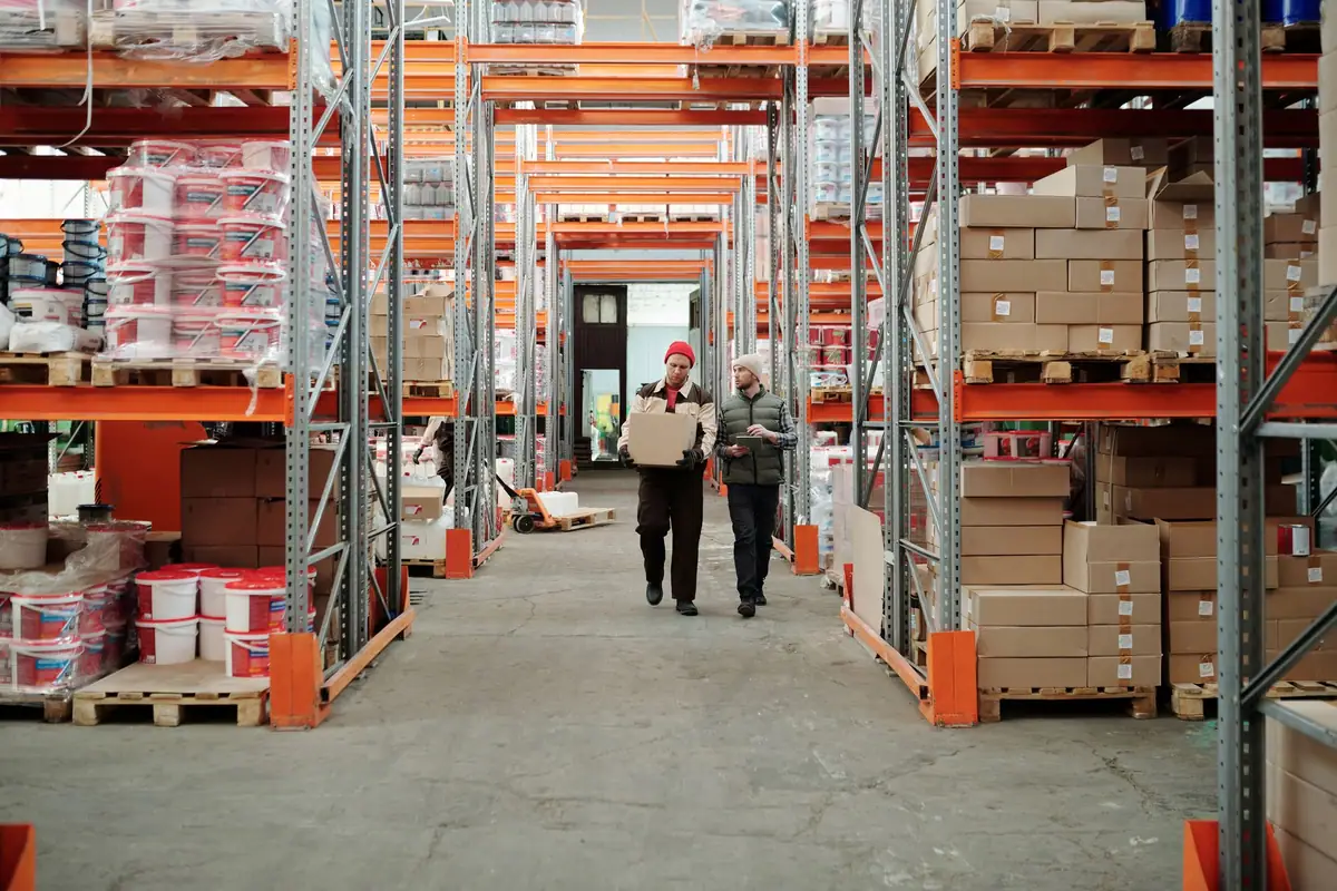 Warehouse aisle lined with tall shelving stocked with boxes and pallets