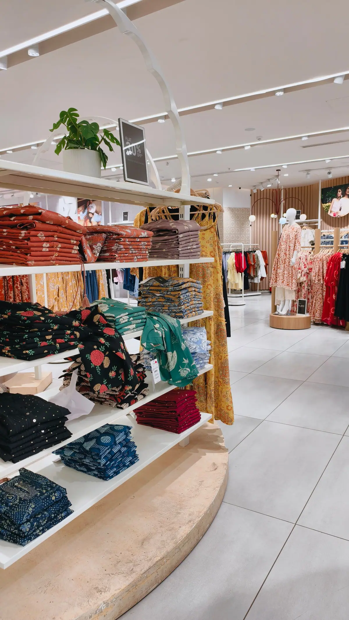 Bright retail store interior with clothing displayed on shelves and racks