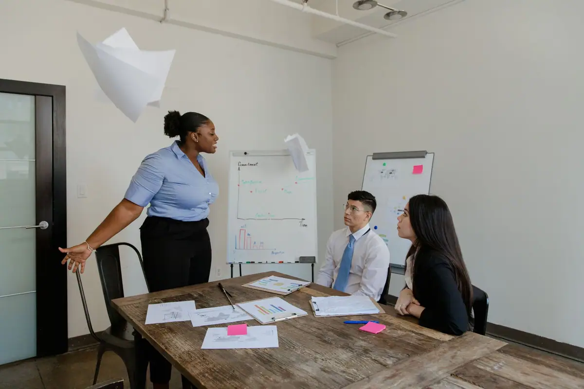 Team meeting around a table while a colleague presents at a flip chart