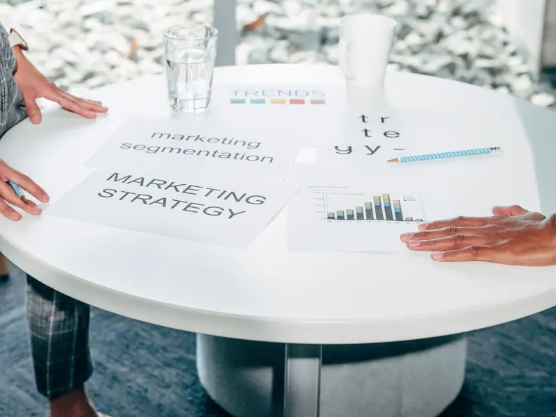 Printed strategy documents spread across a round meeting table